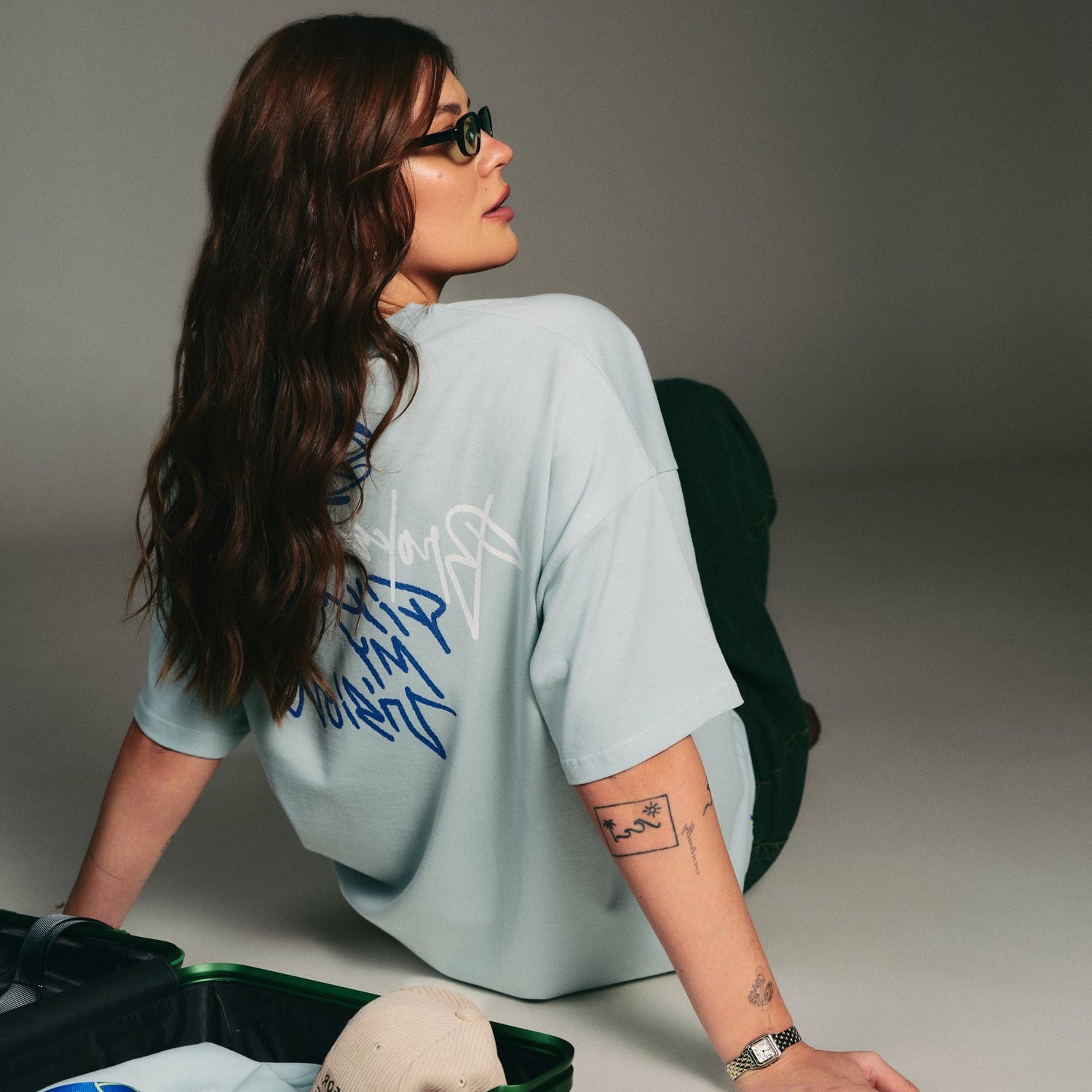 A man in a gray cap faces left, wearing a white T-shirt with artsy text: "Broke My Heart, Fixed My Vision," featuring an eye and heart design. 100% organic cotton hoppers hip hop takeovers oversize t shirt