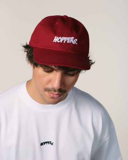 Person wearing a red 'Hoppers' cap and white shirt with brand logo.