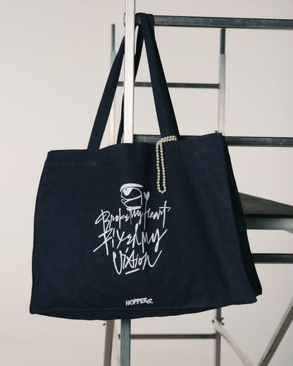 Black tote bag with white text and logo on a metal chair against a white background