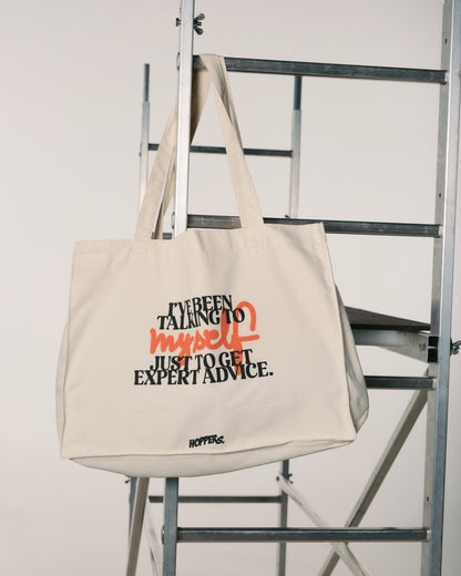 Beige tote bag with humorous text design on a metal ladder.